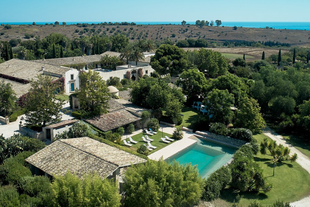 Pool and wellness area, with chapel and main courtyard behind and sea visible in distance